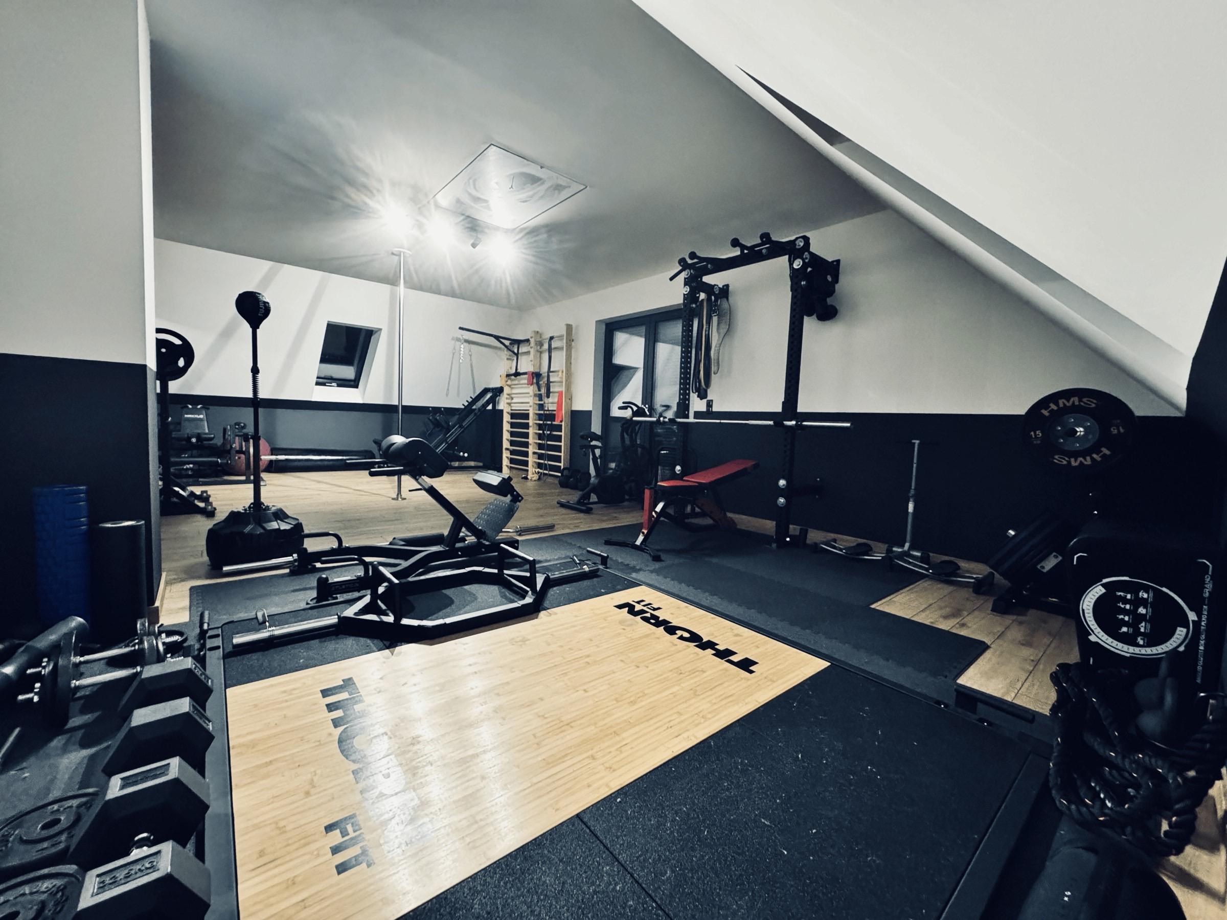 Prywatne studio treningowe Konrada Dumowskiego z widocznym sprzętem siłowym.